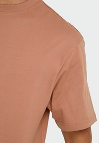 Korte mouw, ronde hals t-shirt gemaakt van zachte, lichte katoen, in een stoffige rozenkleur met een gladde textuur en een eenvoudig design.