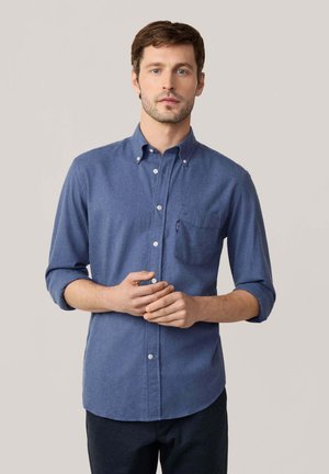 Blue button-up shirt made of a textured fabric, featuring long sleeves rolled to the elbows and a chest pocket on the left side.