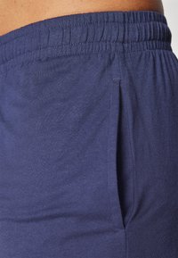 Pantalones de chándal azul marino hechos de algodón suave; cuentan con una cintura elástica y bolsillos laterales con una textura suave.