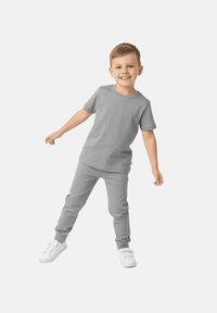 Szary zestaw składający się z koszulki z krótkim rękawem i spodni, charakteryzujący się gładką fakturą i minimalistycznym designem. Całość dopełniają białe sneakersy.