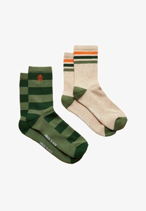 Zwei Paare Crew-Socken; ein Paar grün mit dunkelgrünen Streifen und orangefarbenem Logo, das andere beige mit grünen Zehen und orangefarbenen, schwarzen und grünen Streifen.
