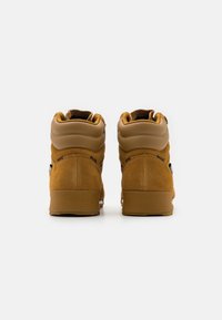 Brown suede high-top sneakers feature a padded collar and smooth rubber sole. Back view shows dual-tone design with minimal hardware accents.