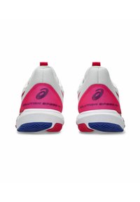Scarpe sportive bianche con accenti rosa sul tallone e suola blu. Presentano un design elegante, un logo prominente e dettagli di colore a contrasto.