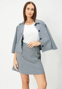 Blå och vit houndstooth-mönstrad jacka och kjolset, med en strukturerad design, knappdetaljer och en slät tygtextur.