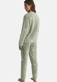 Pyjamas verts texturés avec un motif gaufré, ornés d'accents en forme d'étoiles blanches. Le haut a un col rond et le pantalon est droit.