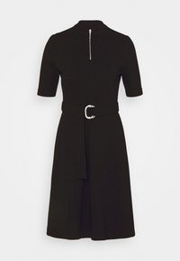 Schwarzes Kleid mit kurzen Ärmeln, figurbetontem Oberteil und einem A-Linien-Rock. Verfügt über einen hohen Kragen und einen Reißverschluss vorne. Enthält einen passenden Gürtel mit einer silbernen Schnalle.