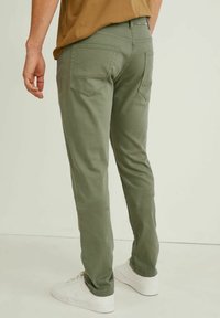 Olivgröna byxor med slim fit, i bomullsblandning, bakfickor och en lätt stretch. Matchat med vita sneakers.