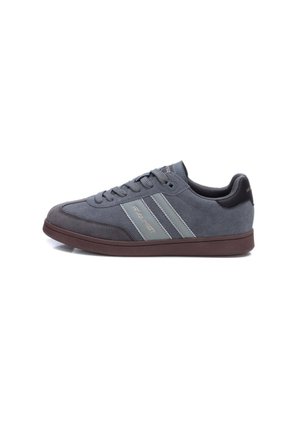 Zapatilla de ante gris con un acabado texturizado, que presenta dos rayas grises y una suela de goma marrón. Cordones y un interior acolchado para mayor comodidad.