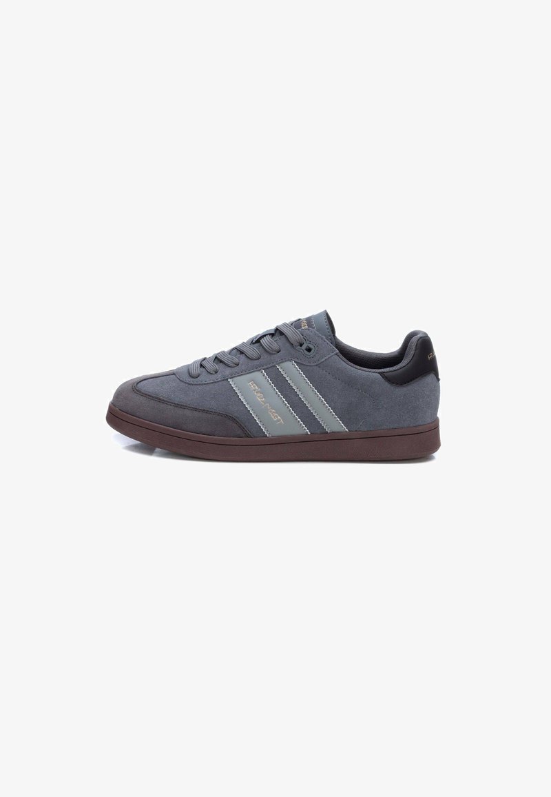 Zapatilla de ante gris con un acabado texturizado, que presenta dos rayas grises y una suela de goma marrón. Cordones y un interior acolchado para mayor comodidad.