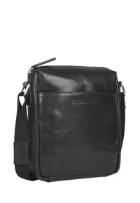 Borsa a spalla in pelle nera con una texture liscia, chiusura con zip, cinturino regolabile e logo impresso sul davanti. Design rettangolare compatto.