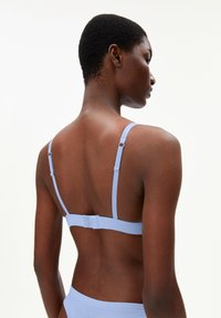 Light blue bra with thin adjustable straps, smooth texture, hook-and-eye closure, minimalistic design, and a simple back style.