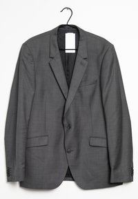 Blazer gris con acabado texturizado, solapas con muesca, dos bolsillos frontales y cierre con un solo botón. Cuelga de un gancho negro.