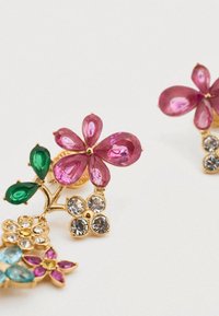 Σκουλαρίκια σε χρυσό τόνο με σχέδια λουλουδιών, που διαθέτουν ροζ και πράσινους πολύτιμους λίθους, διαυγή κρυστάλλινα στοιχεία και περίπλοκες ανθικές λεπτομέρειες σε διάφορα σχήματα και μεγέθη.