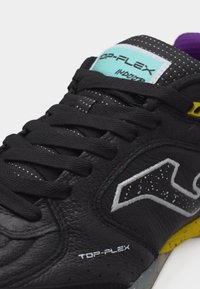 Μαύρο αθλητικό παπούτσι από δέρμα με μαύρα κορδόνια, λευκό και με στίγματα λογότυπο, κίτρινα στοιχεία στη σόλα και μπλε ετικέτα με την ένδειξη "TOP-FLEX INDOOR."