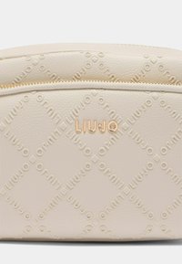 Beige embosovaná taška z faux kůže s prošívaným vzorem, s zlatým zipem a zlatým logem "LIUJO" na přední straně.