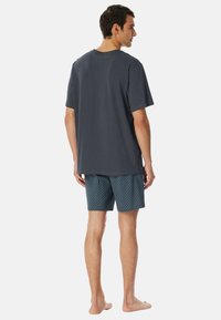 Graues Baumwoll-T-Shirt mit kurzen Ärmeln, kombiniert mit blauen gemusterten Shorts. Die Shorts haben ein geometrisches Design und bieten leichten Komfort.