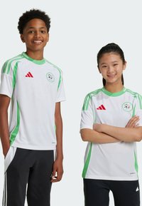 Witte sportshirts met groene accenten en een patroonontwerp, met het Adidas-logo in het rood en een cirkelvormig embleem op de borst.