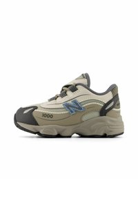 Scarpa sportiva beige realizzata in materiali misti, mesh e pelle. Presenta una punta in gomma grigia e un logo blu, con dettagli testurizzati e lacci.
