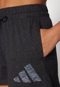 Bermudas pretas com padrão, feitas de tecido macio, com um cós elástico, apresentando um bolso lateral e um logótipo adidas cinza texturizado na bainha.