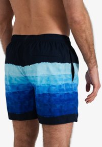 Zwemshorts voor heren in een aflopende blauwtonen, met een elastische tailleband, een achterzak en een gestructureerd, watergerelateerd ontwerp.