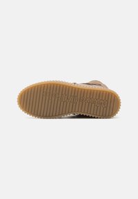 Καφέ καουτσούκ σόλα παπουτσιού με κατακόρυφες ραβδώσεις και κυκλικό σχέδιο πέλματος. Το λογότυπο "Marco O. Polo" είναι εγχαραγμένο. Ανοιχτό καφέ χρώμα.