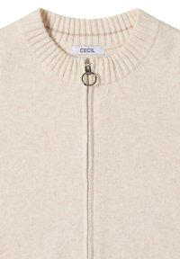 Krämfärgad kofta med ribbad halsringning, framdragkedja och ögla. Mjuk textur med ett subtilt melange-mönster. Märkesetikett: CECIL.