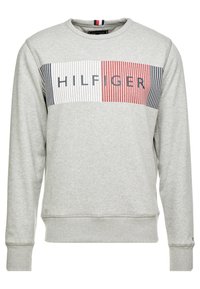 Felpa grigia con collo a giro, caratterizzata da un pannello a righe sul petto in rosso, blu navy e bianco, con la scritta "HILFIGER" in lettere bold.