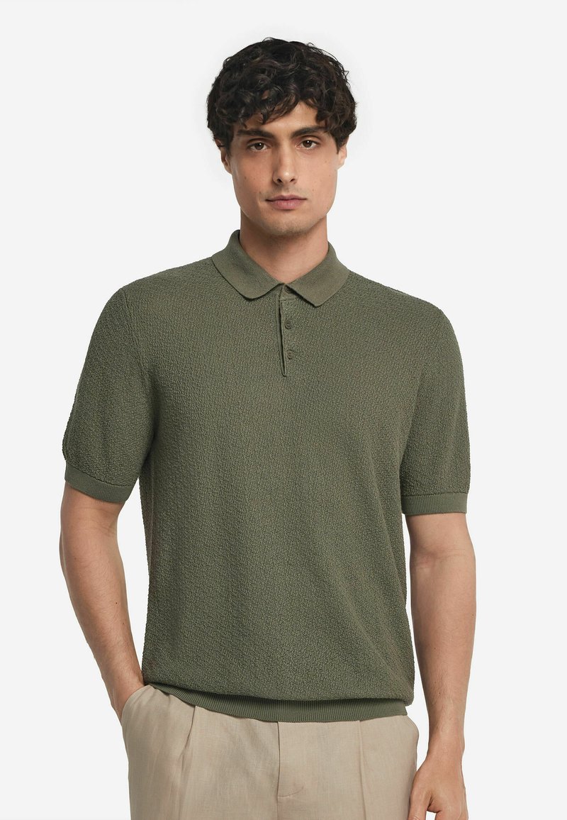 Piké i strukturerad mörkgrön tyg med korta ärmar och krage med knappar, som har ribbade kantar och muddar.