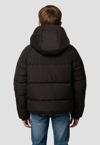 Sort dunjakke med hætte, der har quiltede sektioner og en glat tekstur, kombineret med blå jeans. Set bagfra.