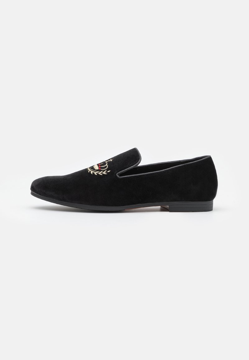 Mocassin en velours noir à enfiler avec couronne dorée brodée et couronne de laurier sur la tige, semelle noire plate, design élégant.