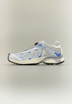 Chaussure de course gris clair avec des accents bleus, tige en mesh, laçage à bascule sécurisé, semelle intermédiaire amortie et semelle extérieure noire texturée.