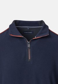 Laiv Blue pulloveri, jossa on vetoketjukaulus, ja siinä on kontrastiväristä punaista ommelta harteilla sekä tekstuurinen kangas. Tagi näyttää "CASA C MODA."