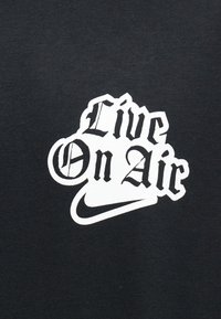 Čierna látka s bielym štýlovaným textom "Live On Air" nad logom Nike swoosh.