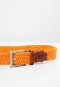 Geweven oranje riem met een metallic zilveren gesp en een bruine leren accent met een logo patch. Gestructureerd patroon overal.