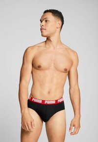 Schwarze Baumwollunterhosen mit rohem Bund, auf dem das "PUMA"-Logo prangt. Eng anliegendes Design, glatte Textur und klassischer Slip-Schnitt.