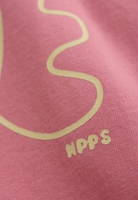 Roze stof met een gele gebogen lijnontwerp en de letters "NPPS" in het geel gedrukt in de rechterbenedenhoek.