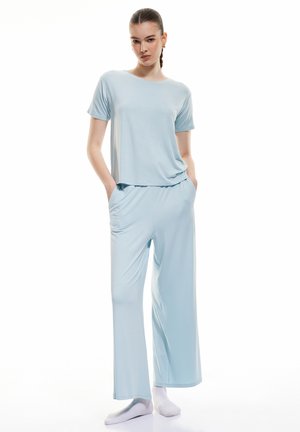 Ensemble de vêtements d'intérieur bleu clair, comprenant un haut à manches courtes avec une coupe ample et un pantalon à jambes larges, fabriqué dans un tissu doux et respirant.