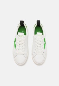 Sneakers bianchi in pelle con un accento laterale verde texturizzato, lacci bianchi e un tab sul tallone nero. Interno foderato in tessuto verde.