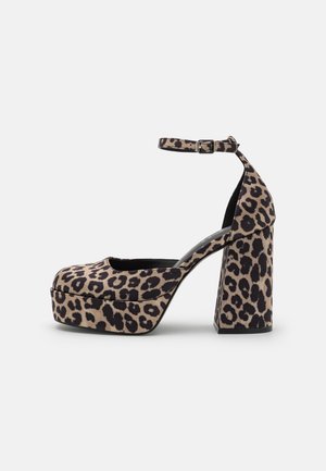 Buty na koturnie z nadrukiem w cętki lamparta, z masywnym obcasem i paskiem wokół kostki. Wykonane z miękkiego materiału, z zaokrąglonym noskiem i teksturowaną powierzchnią.