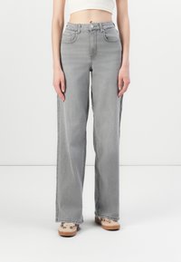 Lichtgrijze wijde jeans gemaakt van denim. Bevat twee voorkeurszakken, een knoopsluiting en een onafgewerkte zoom aan de onderkant.