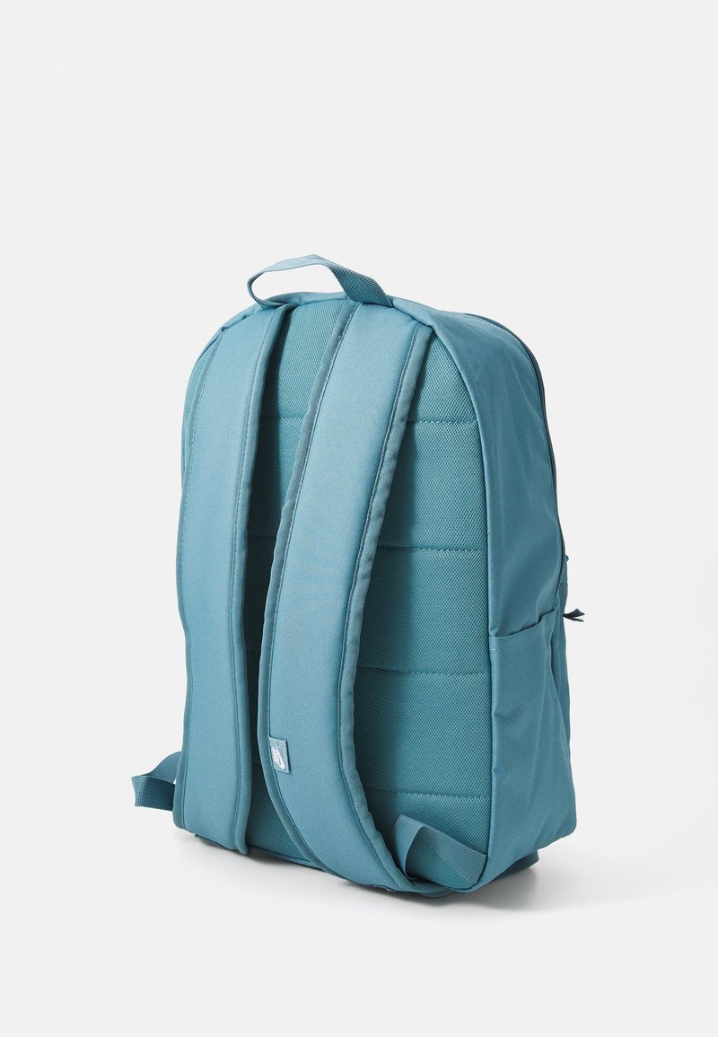 Mochila de tela color aqua con diseño acolchado, correas ajustables y un asa superior. Presenta un cierre de cremallera y un detalle de logo sutil.