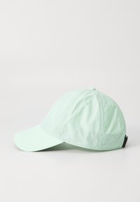 Căciulă verde mentă dintr-un material ușor, având o margine curbată, orificii de ventilație și o curea ajustabilă la spate.