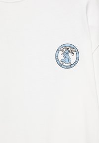 Ange en robe bleue avec des ailes tenant un anneau à l'intérieur d'un cercle avec le texte "FOLLOW YOUR GOALS" sur un t-shirt blanc.