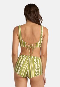 Green striped bikini set featuring a low back, spaghetti straps, and high-waisted bottoms with wave and line patterns. Ties at the back.