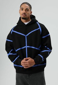 Zwarte hoodie met lichtblauwe geometrische lijnen. Gemaakt van een katoenmengsel, oversized pasvorm, verstelbare capuchon, voorkangoeroezak, geribbelde boorden.
