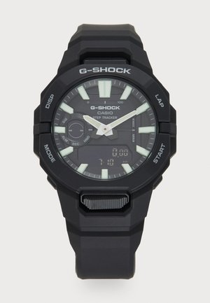 Czarny zegarek G-Shock z wyświetlaczem cyfrowym i analogowym, świecącymi znacznikami, teksturowanym paskiem oraz wieloma przyciskami funkcyjnymi z boku.