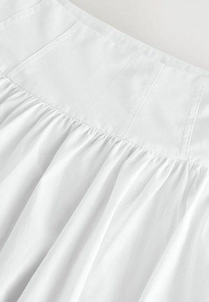 Falda blanca con un top ajustado y textura fruncida. Hecha de una tela ligera, con costuras sutiles y una caída suave y fluida.