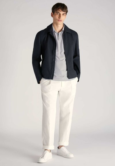 Navy blazer z kołnierzem, szary polo, białe spodnie o prostym kroju i białe trampki. Prosty design i nowoczesny krój.