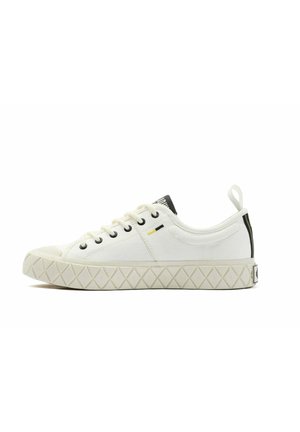 White canvas sneaker with a round toe, black eyelets, and a rubber sole featuring a textured diamond pattern. Accented with a yellow detail.