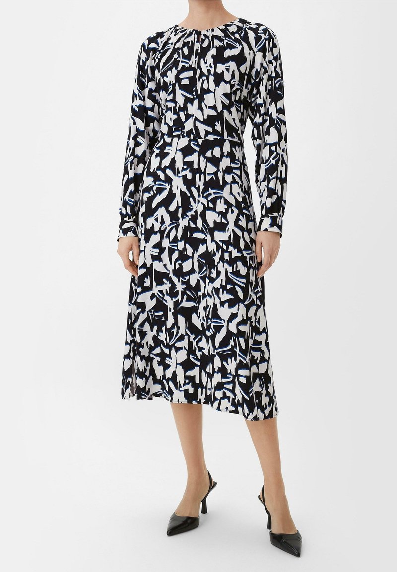 Vestido de manga larga en negro, blanco y azul con un patrón abstracto; de longitud a la rodilla, con escote redondo y ligero fruncido en los hombros.